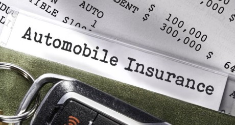 A car insurance policy is behind a car key. | Can You Switch Car Insurance Companies Mid-Policy?